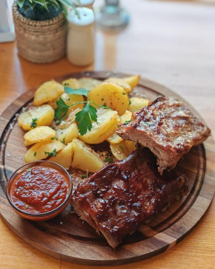 Scăriță de porc cu sos de miere, cartofi copți, sos picant și salată